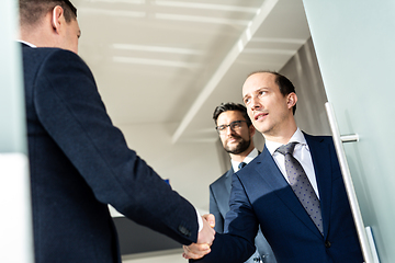 Image showing Group of confident business people greeting with a handshake at business meeting in modern office or closing the deal agreement by shaking hands.