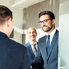 Image showing Group of confident business people closing the deal agreement by shaking hands at business meeting.