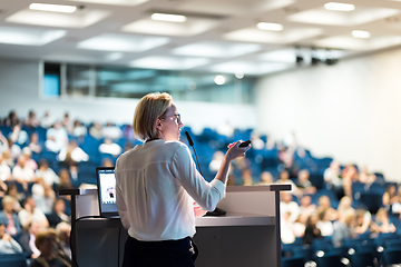 Image showing Female speaker giving a talk on corporate business conference. Unrecognizable people in audience at conference hall. Business and Entrepreneurship event.