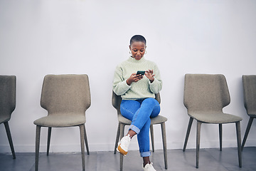 Image showing Black woman, phone and sitting on a chair in a waiting room with internet connection for social media. African female person in line for recruitment interview with a smartphone for communication app