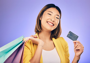 Image showing Asian woman, credit card and shopping bag in studio portrait with smile for deal, sale or discount by background. Japanese girl, retail and happy with banking, budget or luxury by purple background