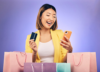 Image showing Japanese woman, credit card and shopping bag in studio with smile for deal, sale or discount with fintech. Gen z asian girl, retail and happy with banking, budget or luxury gift by purple background