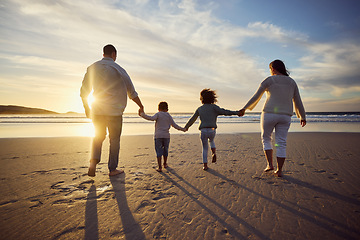 Image showing Sunset, beach and back of family holding hands and walking on holiday, summer vacation and weekend. Nature, travel and mother, father and children by ocean for bonding, adventure and quality time