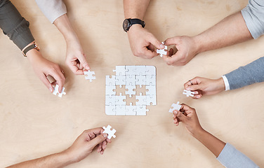 Image showing Puzzle, hands and office group with planning and problem solving at a table. Above, teamwork and company employee team with strategy, collaboration and connection process for decision and solidarity