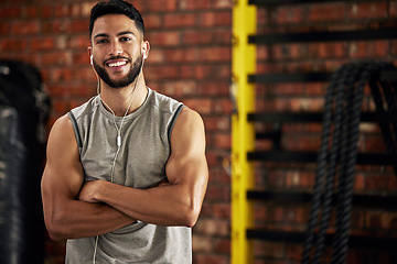 Image showing Fitness, earphones and portrait of man in gym, arms crossed and confident smile in mockup space. Happiness, workout and happy face of bodybuilder streaming music for health, indoor training and pride