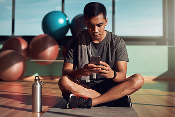 Image showing Gym, phone and man on floor with mobile app for fitness schedule, reading email or checking social media. Internet search, cellphone and workout, healthy male athlete on mat in pilates or yoga studio