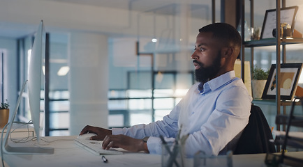 Image showing Business man, focus and working on a computer at night while typing an email or report. A serious black male entrepreneur with technology for networking, internet connection and online research