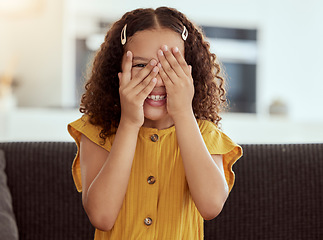 Image showing Hide and seek, kid and girl portrait with hands to face in a home with a smile. Game, fun and playing child on a living room sofa with happiness and fun on a couch with youth and hiding feeling shy