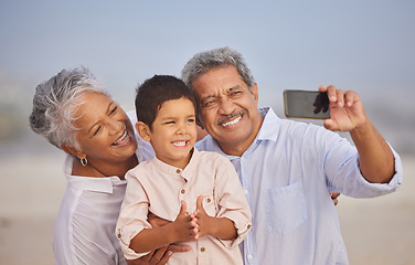 Image showing Selfie, happy and grandparents with child at beach for vacation, bonding and generations. Picture, travel and young boy with senior man and woman in nature for smile, happiness and technology