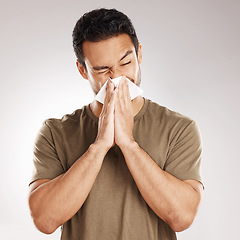 Image showing Man sneezing, blowing nose and tissue with virus and health issue against a grey studio background. Male person, guy and model suffering from cold, sinus and hayfever with sickness and allergies