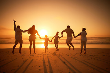 Image showing Family, holding hands beach at sunset and jump, freedom and travel with grandparents, parents and kids. Back view, orange sky and generations and people outdoor with silhouette and vacation in Mexico