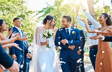 Image showing Happy, wedding ceremony and couple walking with petals and guests throw in celebration of romance. Romantic, flowers and bride with bouquet and groom with crowd celebrating at outdoor marriage event.