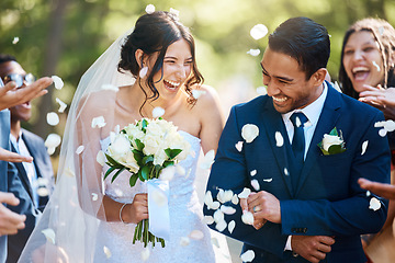 Image showing Love, wedding and couple walking with petals and guests throwing in celebration of romance. Happy, smile and young bride with bouquet and groom with crowd celebrating at the outdoor marriage ceremony