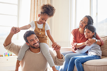 Image showing Dad, mom and children in home, shoulders and happiness with playing games, hug or bonding in lounge. Father, mother and daughter with care, love and together with embrace, quality time or living room