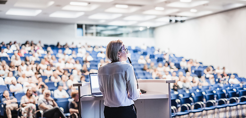 Image showing Female speaker giving a talk on corporate business conference. Unrecognizable people in audience at conference hall. Business and Entrepreneurship event.