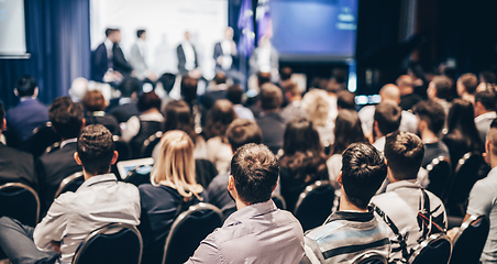 Image showing Speaker giving a talk in conference hall at business event. Rear view of unrecognizable people in audience at the conference hall. Business and entrepreneurship concept.