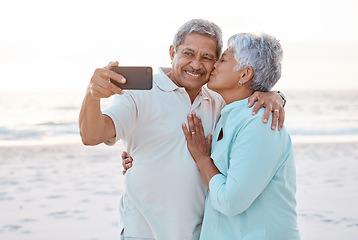 Image showing Senior couple, kiss and beach for selfie, profile picture or online post together in nature. Happy elderly woman kissing man on ocean coast for photo, memory or social media vlog in the outdoors