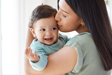 Image showing Mom, kiss and holding baby in home for love, care and quality time together to nurture childhood development. Mother, kissing and carrying infant girl kid for support, happiness and comfort of parent