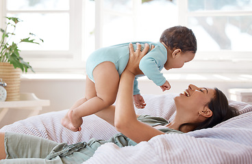 Image showing Happy mother, play and holding baby on bed for love, care and quality time together at home. Mom, smile and carrying playful infant kid, newborn and laughing in bedroom for comfort, relax and support