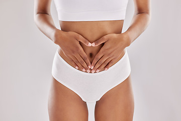 Image showing Heart, hands and gut health by woman in lingerie in studio for digestion, wellness and diet on grey background. Lose weight, detox and finger emoji by female model in underwear for feminine hygiene