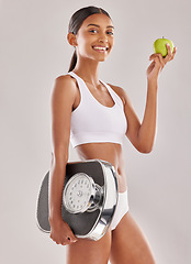 Image showing Woman, body and apple with scale and lose weight, smile in portrait with health and nutrition on studio background. Happy female model, healthy food and fruit with diet, detox and vegan lifestyle