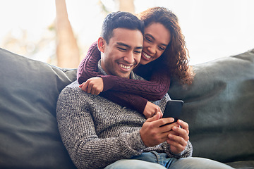 Image showing Happy couple, phone and relax on sofa with social media, internet and online streaming service at home. Young interracial woman and man or partner on video call, connection or hug or love on couch