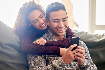 Image showing Happy couple, phone and hug on couch with internet meme, reading news or online streaming service at home. Young interracial woman and man or partner on funny website, connection and love on sofa