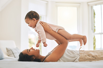 Image showing Mother, lifting baby and bedroom in family home for bonding, security or quality time. Happy woman or mom and girl child relax together on bed for development, trust and support or care for happiness