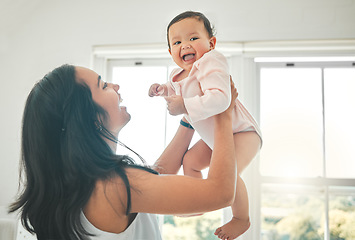 Image showing Funny, mother and lifting baby, care and bonding together with infant in home. Smile, mama and raise newborn, child or kid, playing and having fun, happiness or enjoying quality time with family love