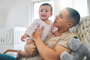 Image showing Father, holding baby and crying in a family home while hungry, tired or sad. Frustrated and confused man or dad and girl child cry on a sofa while sick, colic or sleepy on a living room couch