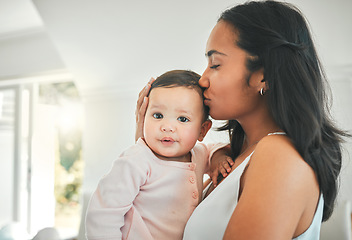 Image showing Mother, holding baby and kiss in a family home for love, security and quality time. Woman or mom and girl child relax together in a house for development, trust and support or care on mothers day