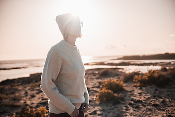 Image showing Portrait of young stylish woman wearing wool sweater, wool cap and sunglasses on long sandy beach in spring