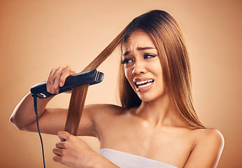 Image showing Woman with flat iron, haircare fail and anxiety about heat damage with hairloss isolated on studio background. Electric hair straightener, female model worried about keratin treatment and hairstyle