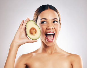 Image showing Woman, beauty and avocado in studio, excited and health for wellness, facial glow and white background. Girl, model and healthy skin with fruit, makeup or cosmetics for self care, funny face or smile