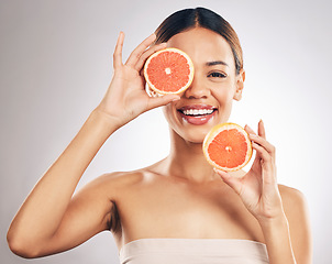 Image showing Portrait, skincare and happy woman with grapefruit in studio fo organic, cosmetic or treatment on grey background. Citrus, face and female model with fruit for eco, vegan or skin detox with vitamin c