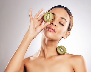 Image showing Skincare, kiwi and woman in studio for wellness, beauty or body care with natural cosmetic on grey background. Organic, treatment and female with fruit for vegan, eco or antioxidant, luxury or facial