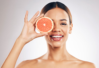 Image showing Grapefruit, skincare and woman smile in studio for natural cosmetic, eco or beauty on grey background. Citrus, facial and female model relax with fruit for vegan, detox and vitamin c for glowing skin