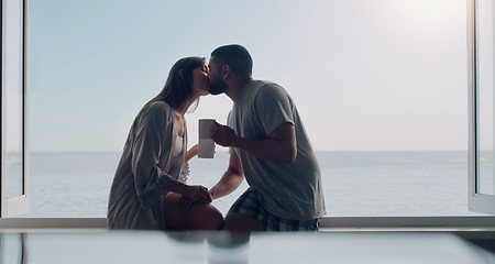 Image showing Couple, kiss and coffee in morning by window with love, romance and care on holiday by ocean with sunshine. Man, woman and trust with drink, espresso or matcha on vacation by sea with bond in summer