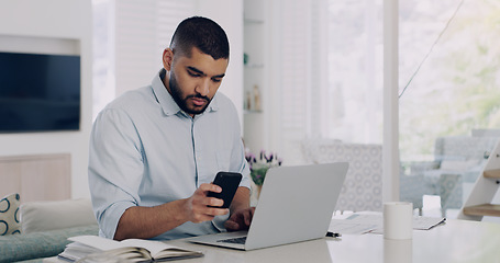 Image showing Man, remote work and smartphone at laptop in home for reading notification, digital planning and online information. Male freelancer, cellphone and working on computer, internet and check mobile app