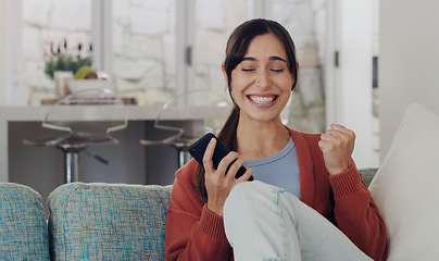 Image showing Woman, phone and celebration on sofa, winning and smile with success, profit or online gambling in home. Girl, smartphone and winner with fist to celebrate esport, web casino or achievement on couch