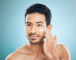 Image showing Wellness, skincare and man with face cream in a studio for a natural, moisturizing and health routine. Male model with facial spf, lotion or moisturizer for dermatology treatment by a blue background