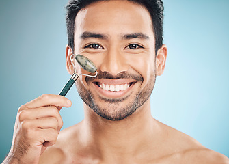 Image showing Beauty, portrait or happy man with jade roller, facial product for soft or healthy skincare on studio background. Relaxing, grooming or male model smiling with dermatology cosmetics for face massage