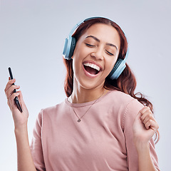 Image showing Mobile, headphones or happy girl dancing to music or singing radio songs in studio on white background. Dance, smile or excited woman streaming or listening to audio playlist with cellphone or energy