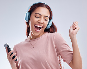 Image showing Happy woman with mobile in headphones singing music or dancing to radio audio in studio on white background. Dance, smile or girl streaming or listening to song playlist in freedom with cellphone