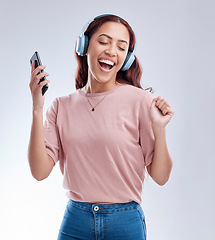 Image showing Happy girl with mobile in headphones dancing music or singing a radio audio in studio on white background. Dance, smile or woman streaming or listening to song playlist in freedom with cellphone