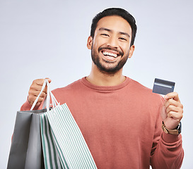 Image showing Man is laughing with shopping bag, credit card and happy about discount at boutique isolated on studio background. Humor, funny and male person with payment for purchase, luxury and retail with sale