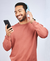 Image showing Man, smile and smartphone with headphones, listening to music or podcast isolated on studio background. Male person is enjoying radio streaming, online with wireless technology and playlist on app