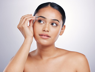 Image showing Face, woman with tweezers and makeup against a studio background. Cosmetics or dermatology, skincare or beauty treatment and female person shaping her eyebrows for facial care against backdrop