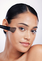 Image showing Face, beauty and woman with a makeup brush in studio for skin glow, shine and cosmetics. Portrait of a female model with cosmetic tools in hand for self care and facial powder on a white background