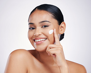 Image showing Woman in portrait, cream on face and beauty with skincare, smile and moisturizer isolated on studio background. Happy female model apply lotion, dermatology and cosmetic product with skin glow